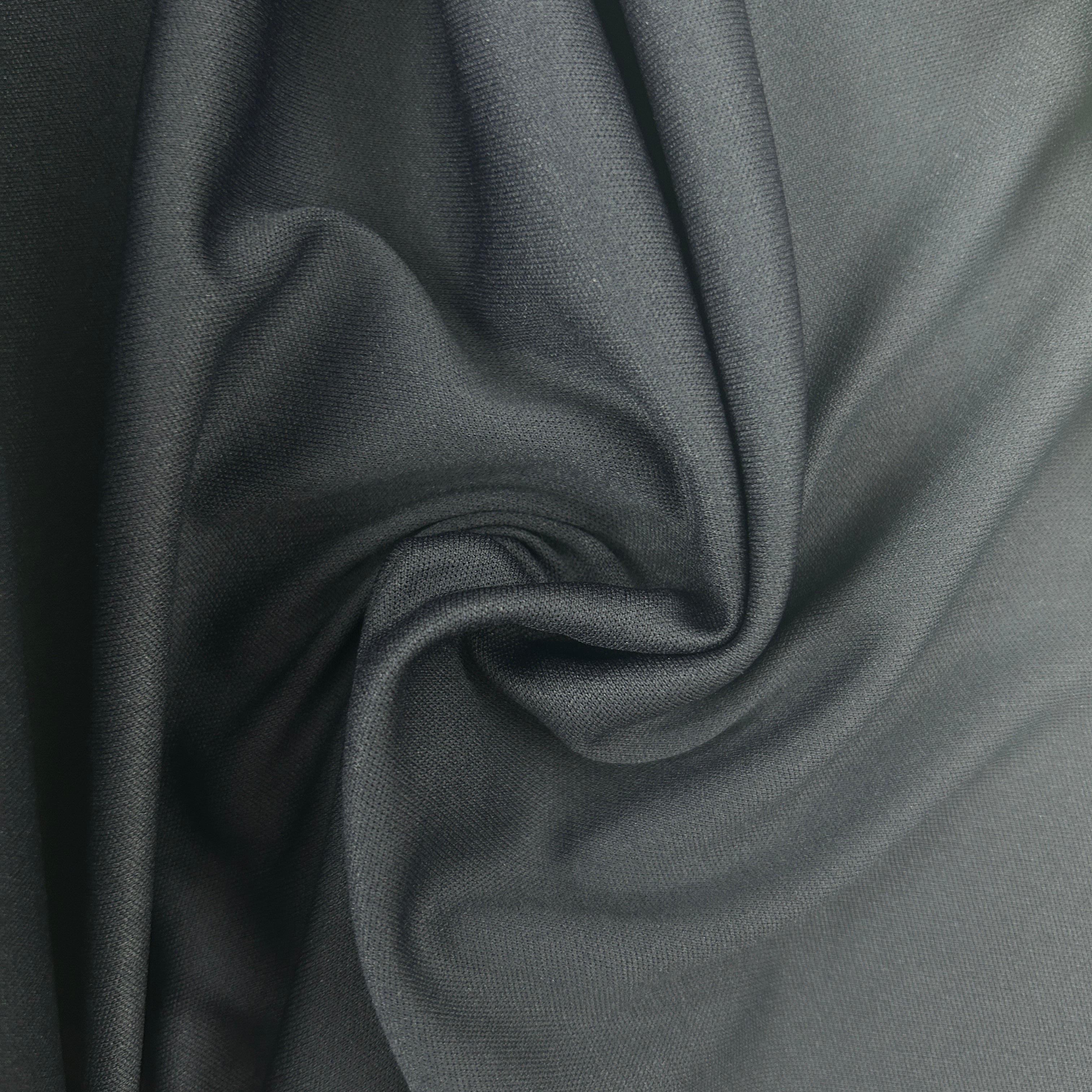 A close-up of draped dark gray fabric with a soft, matte texture and subtle sheen, arranged in elegant folds.