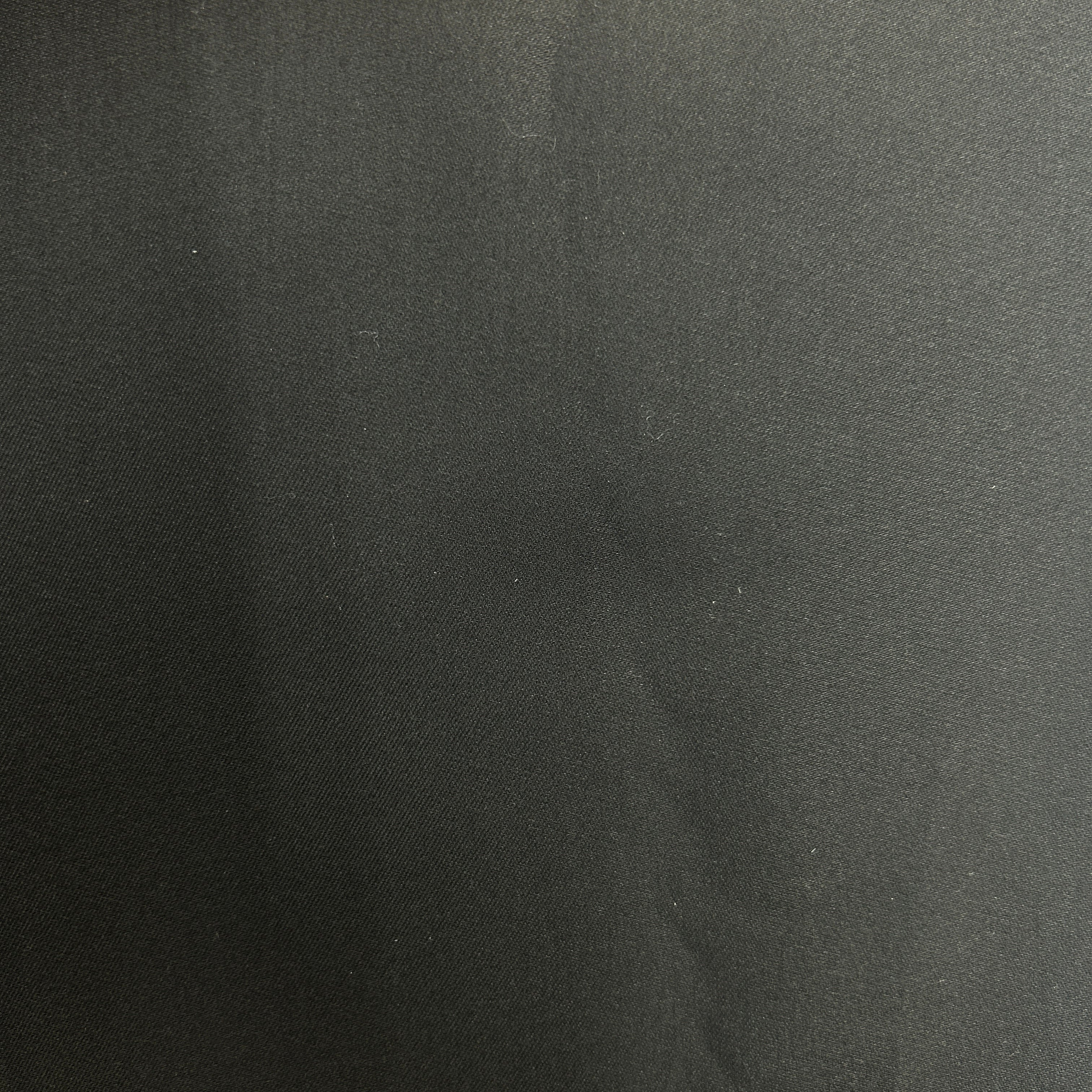 A close-up of a dark charcoal gray textured fabric surface.