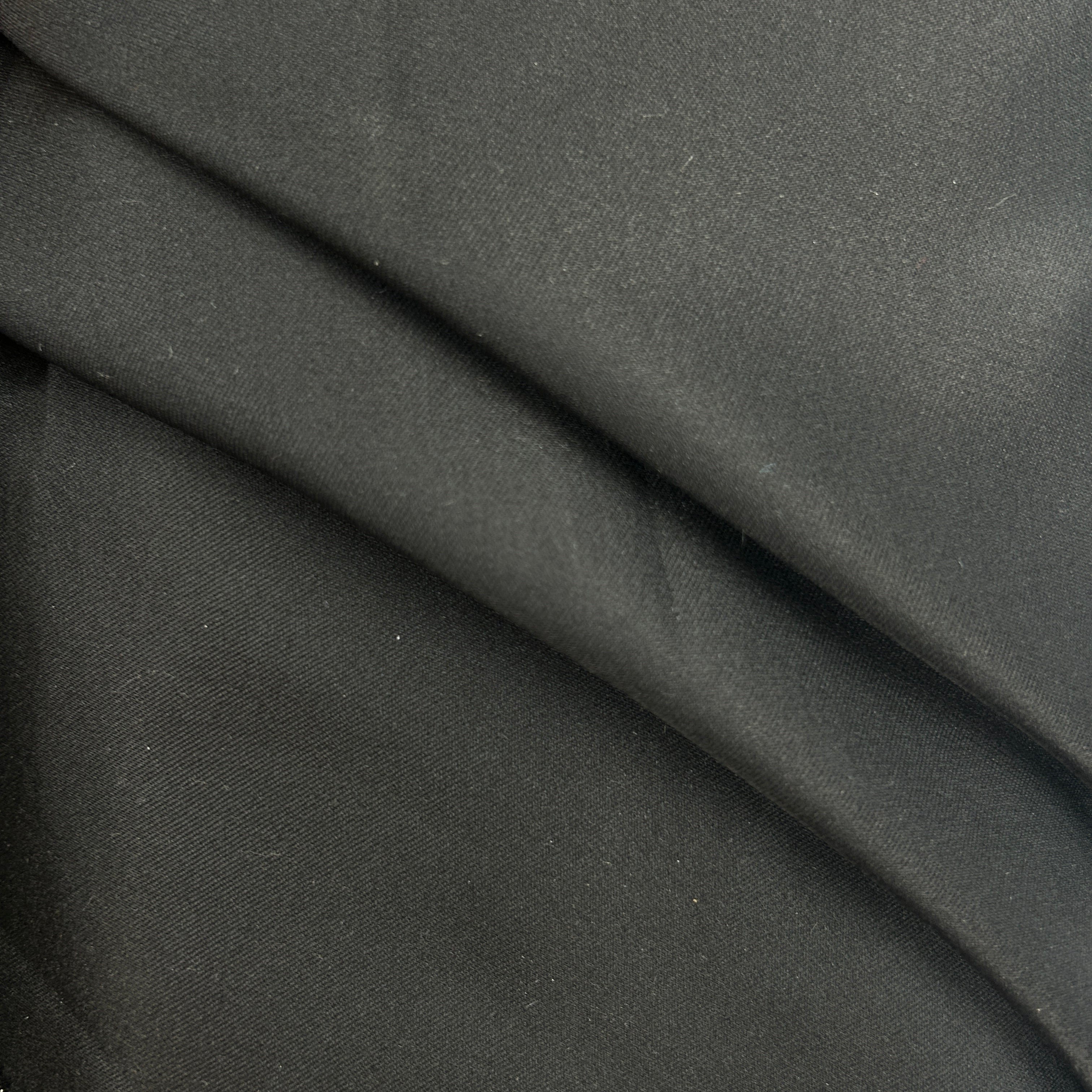 A close-up of draped black fabric showing its texture and soft folds.
