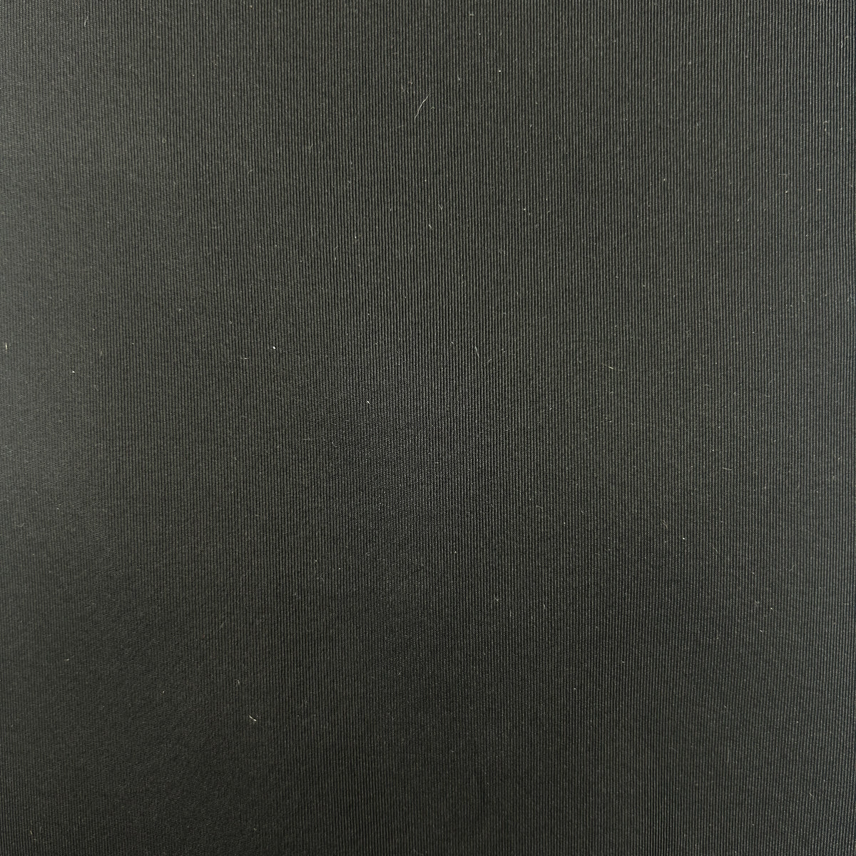 Close-up of black silk grosgrain fabric showing its fine, vertical ribbed texture and subtle sheen.