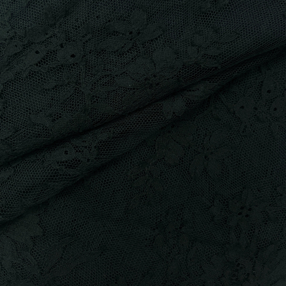 Close-up of black floral lace fabric with a sheer mesh background and delicate embroidered pattern, draped with soft folds.
