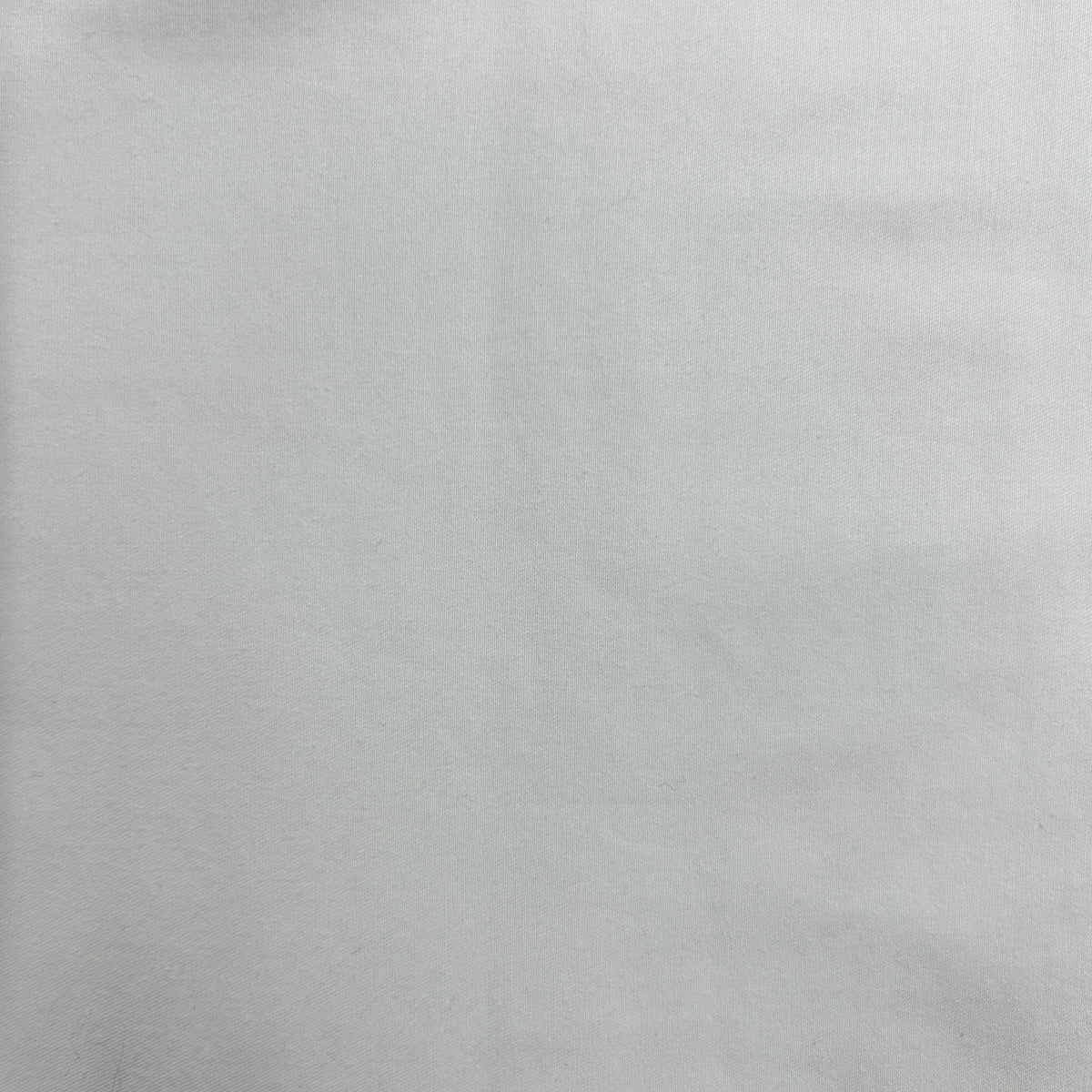 A close-up of a light gray textured material, likely a fabric or leather-like surface.