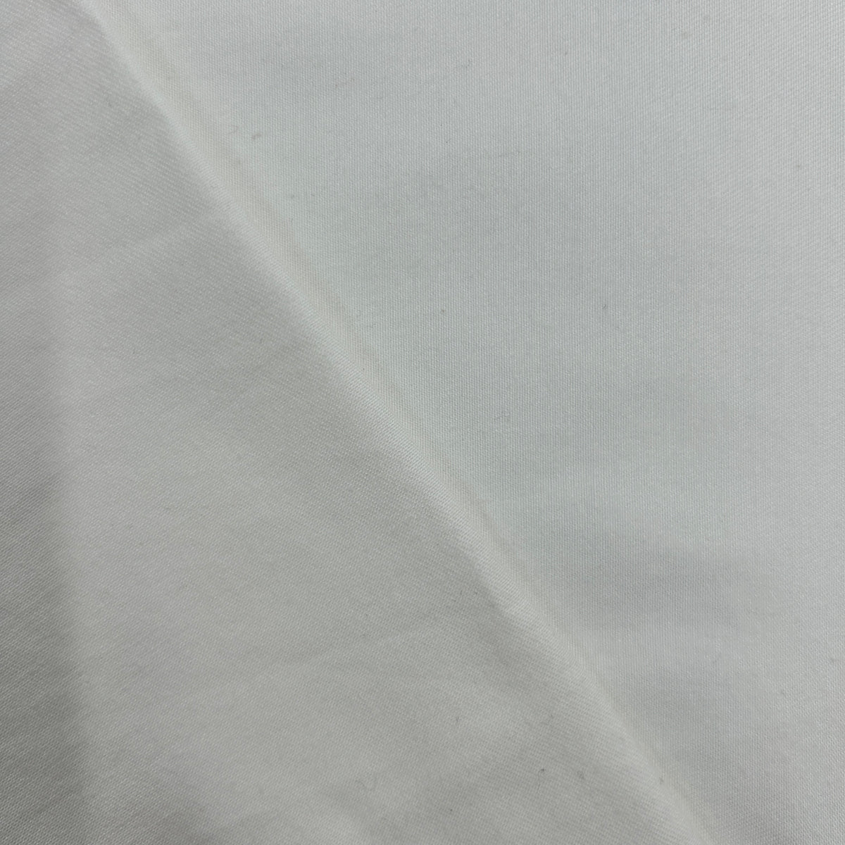 A close-up of plain white fabric with a soft diagonal fold showing the material texture.
