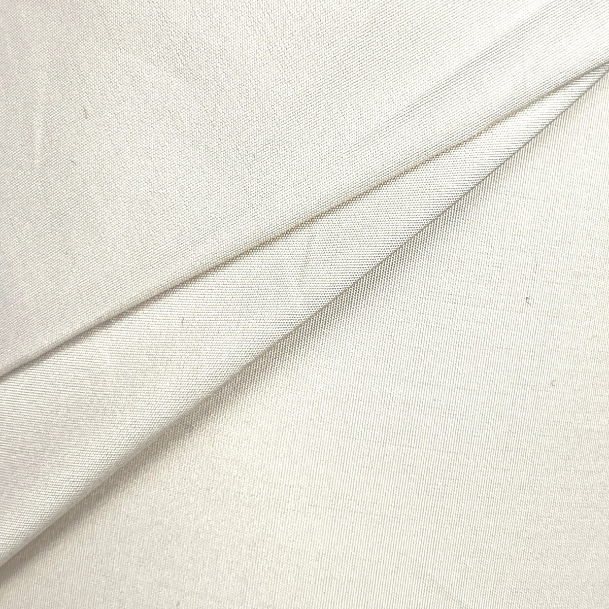 A close-up of draped off-white fabric with a soft, slightly textured surface and gentle folds.