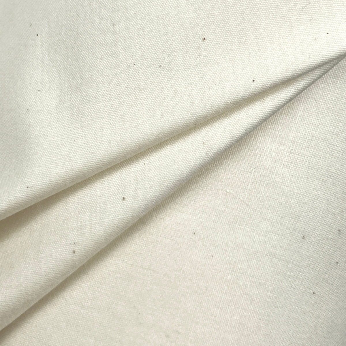 A close-up of off-white fabric with a soft texture and a diagonal fold.