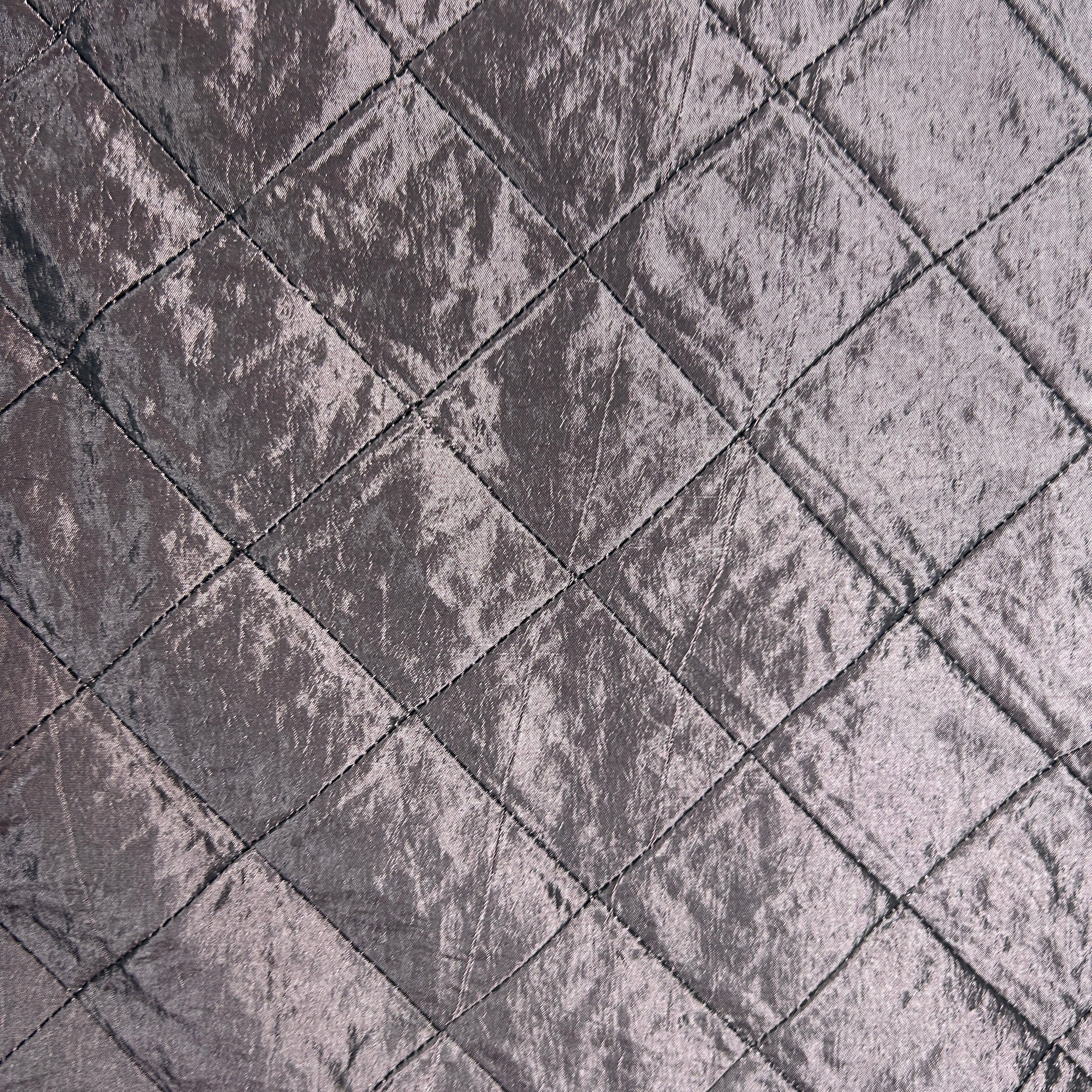 A close-up of a textured fabric with a diamond quilted pattern in a dusty mauve-gray color.