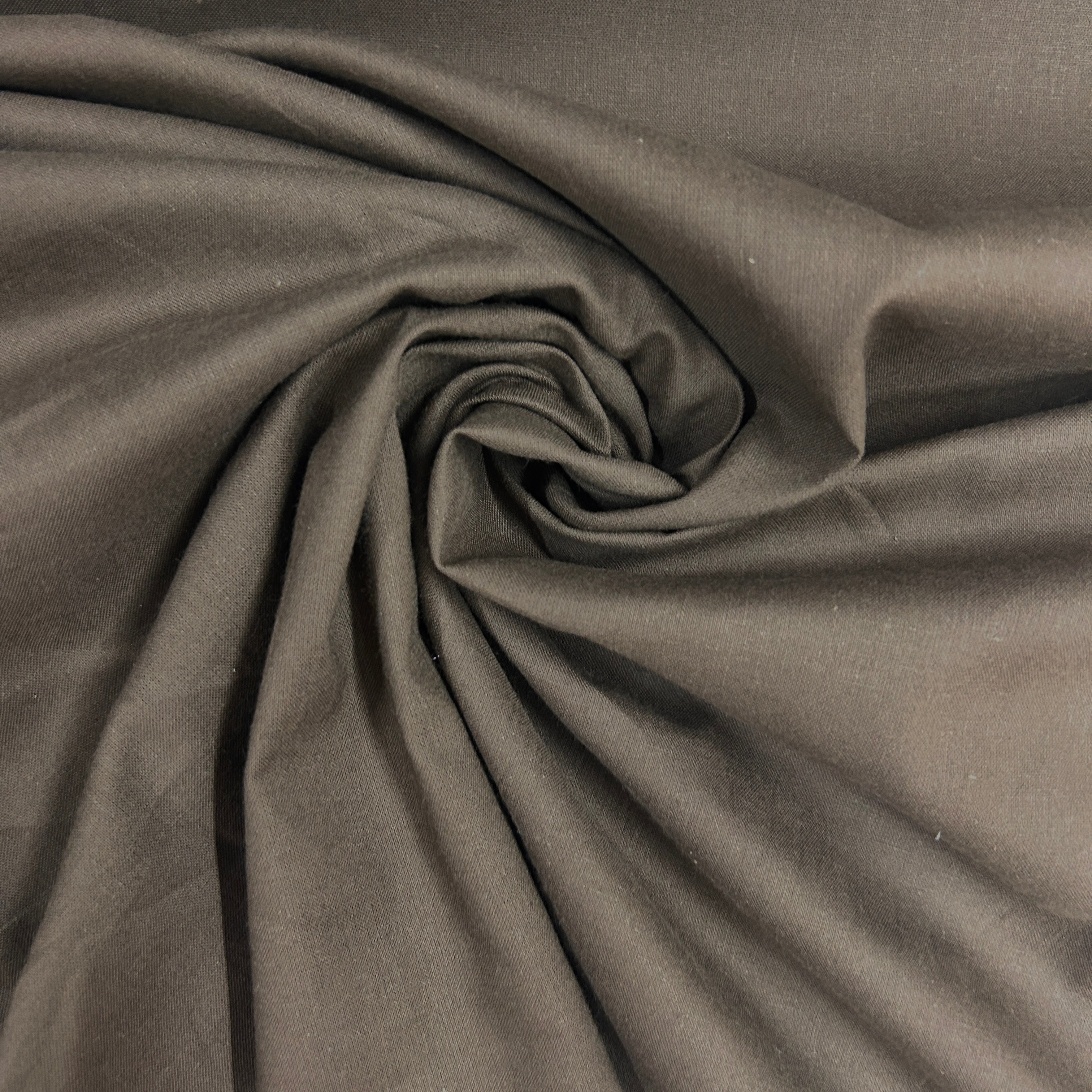 A close-up of draped dark gray fabric arranged in a spiral swirl, showing the material's texture and soft folds.
