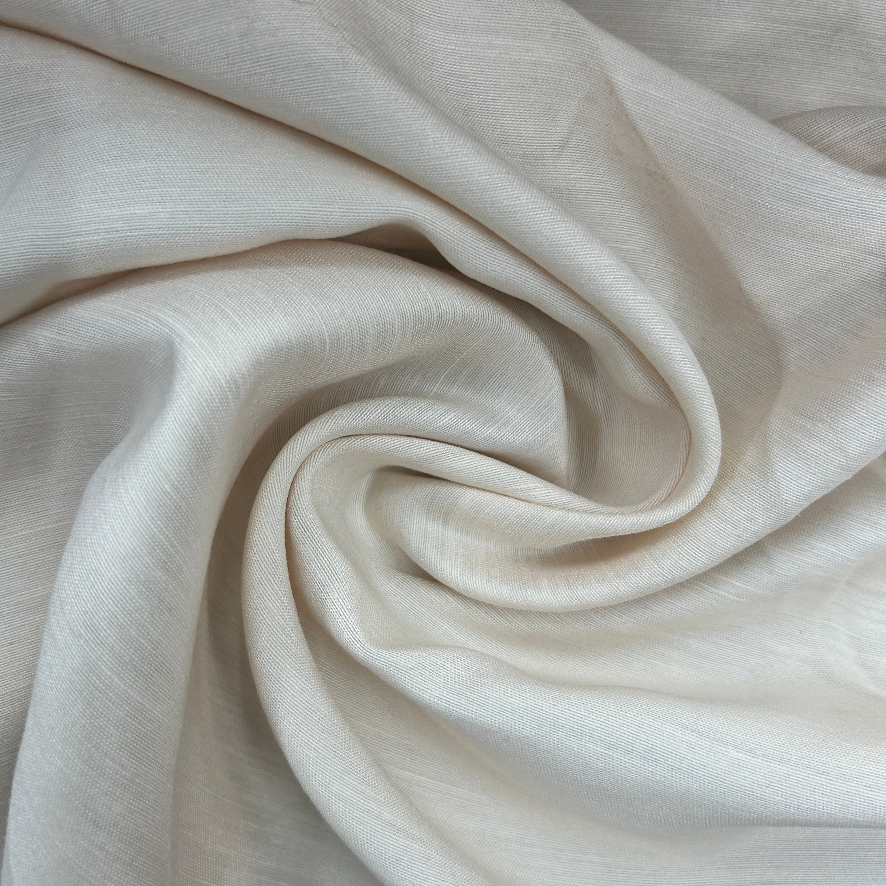 A close-up of draped off-white fabric with a soft, slightly sheer texture arranged in a spiral pattern.