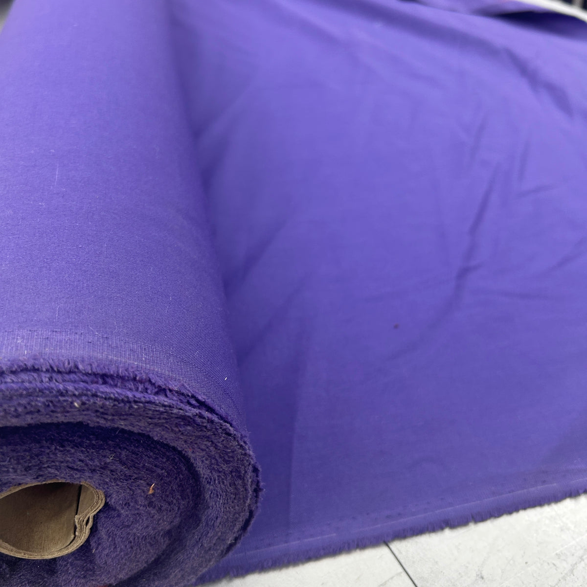 A roll of solid purple fabric, shown partially unrolled to display its texture and color.