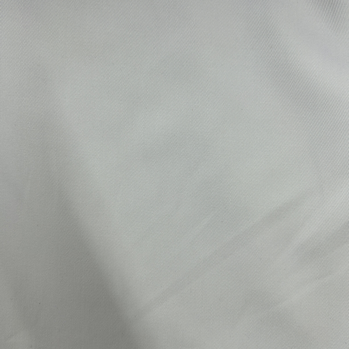 A close-up of light gray fabric with a fine woven texture and soft folds.