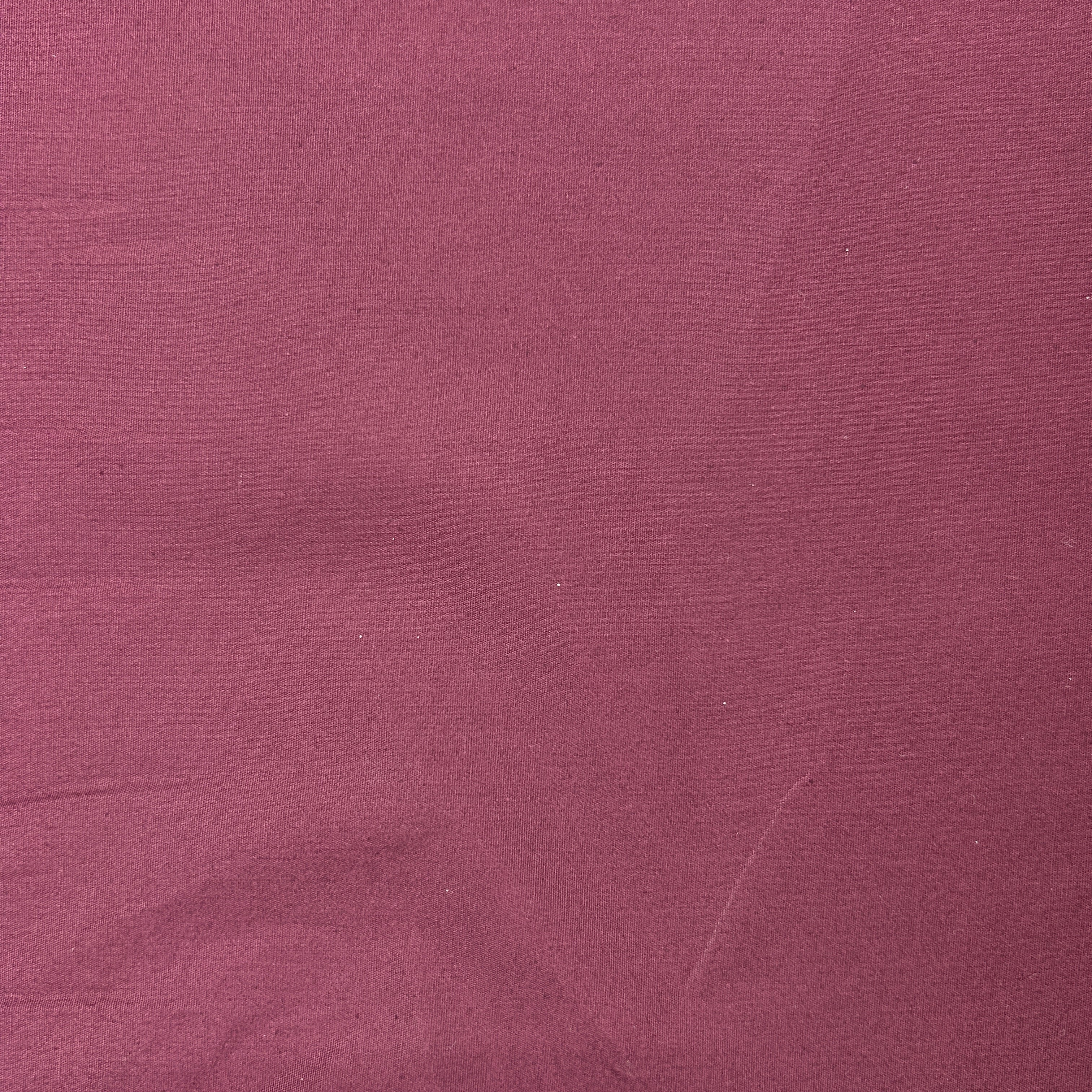 A close-up of a dusty rose or mauve-colored fabric texture filling the entire frame.