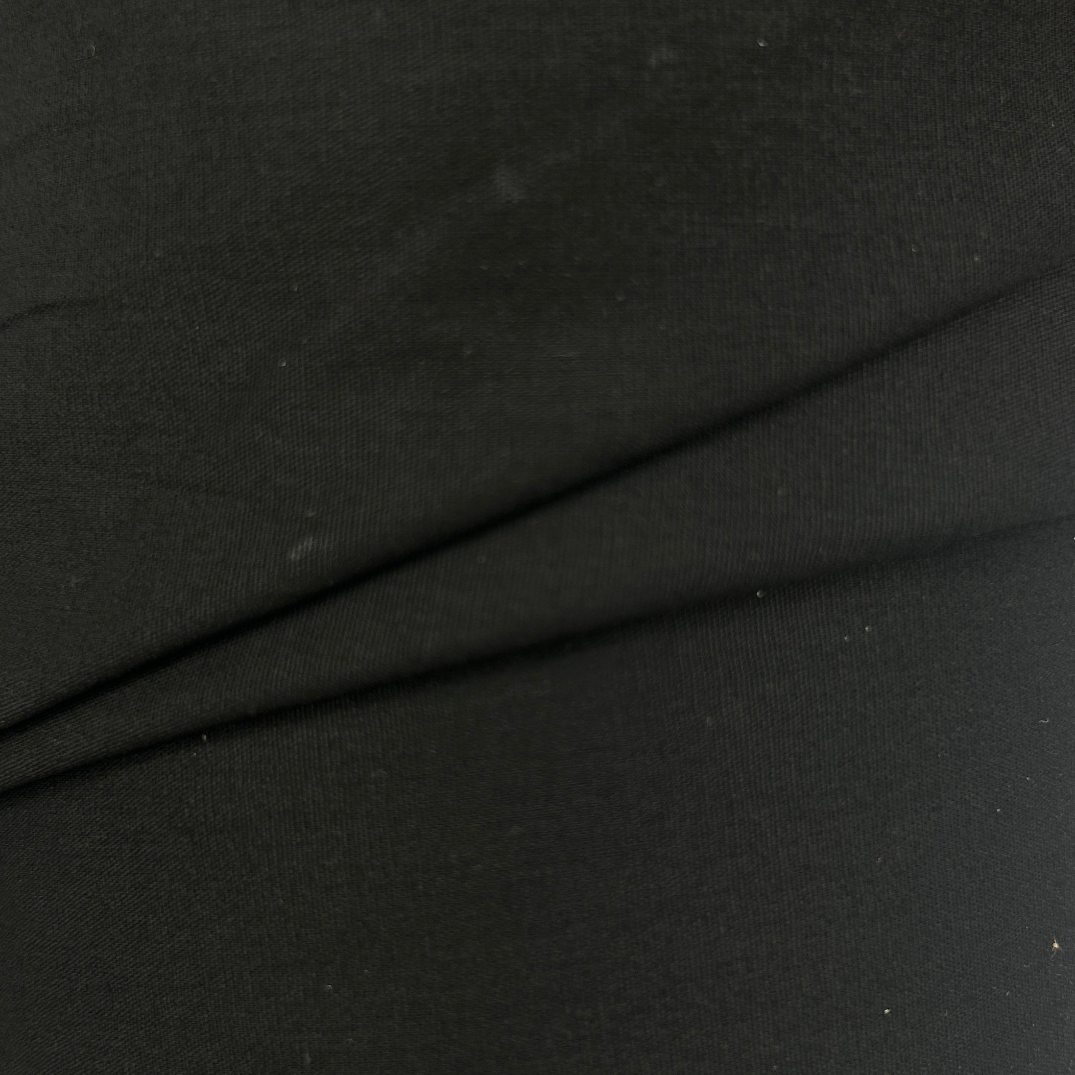 A close-up of black fabric with a fine knit texture and a diagonal fold running across the center.