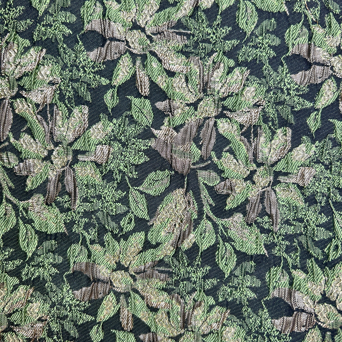 Close-up of green floral brocade upholstery fabric with intricate leaf and flower patterns.