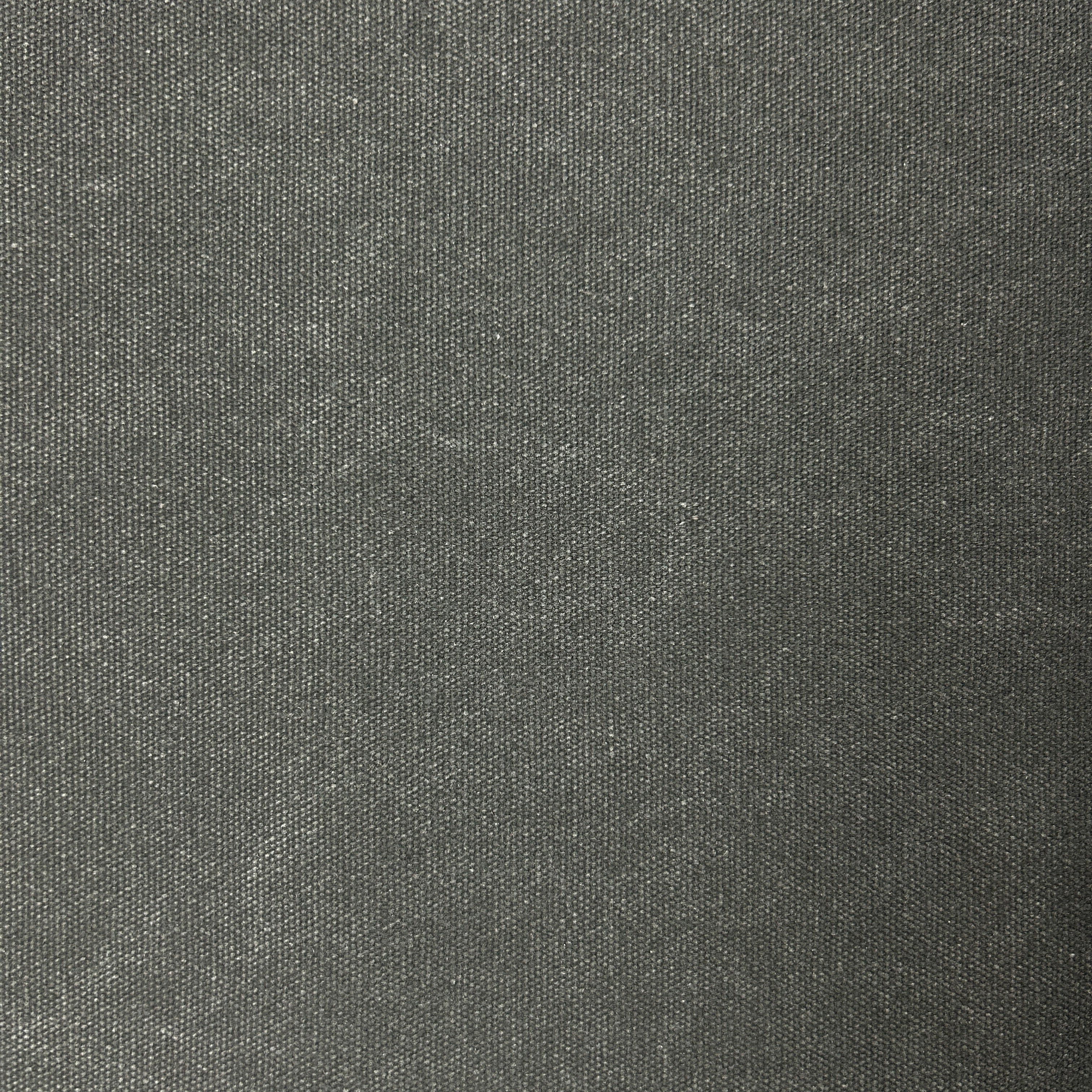 Close-up texture of black poly cotton heavy waxed canvas fabric with a stiff, woven finish.