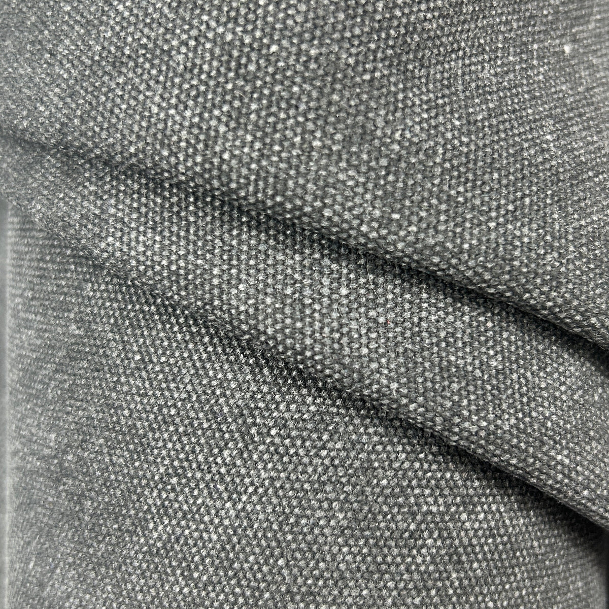 Close-up of black poly cotton heavy waxed canvas fabric with a stiff, textured weave.