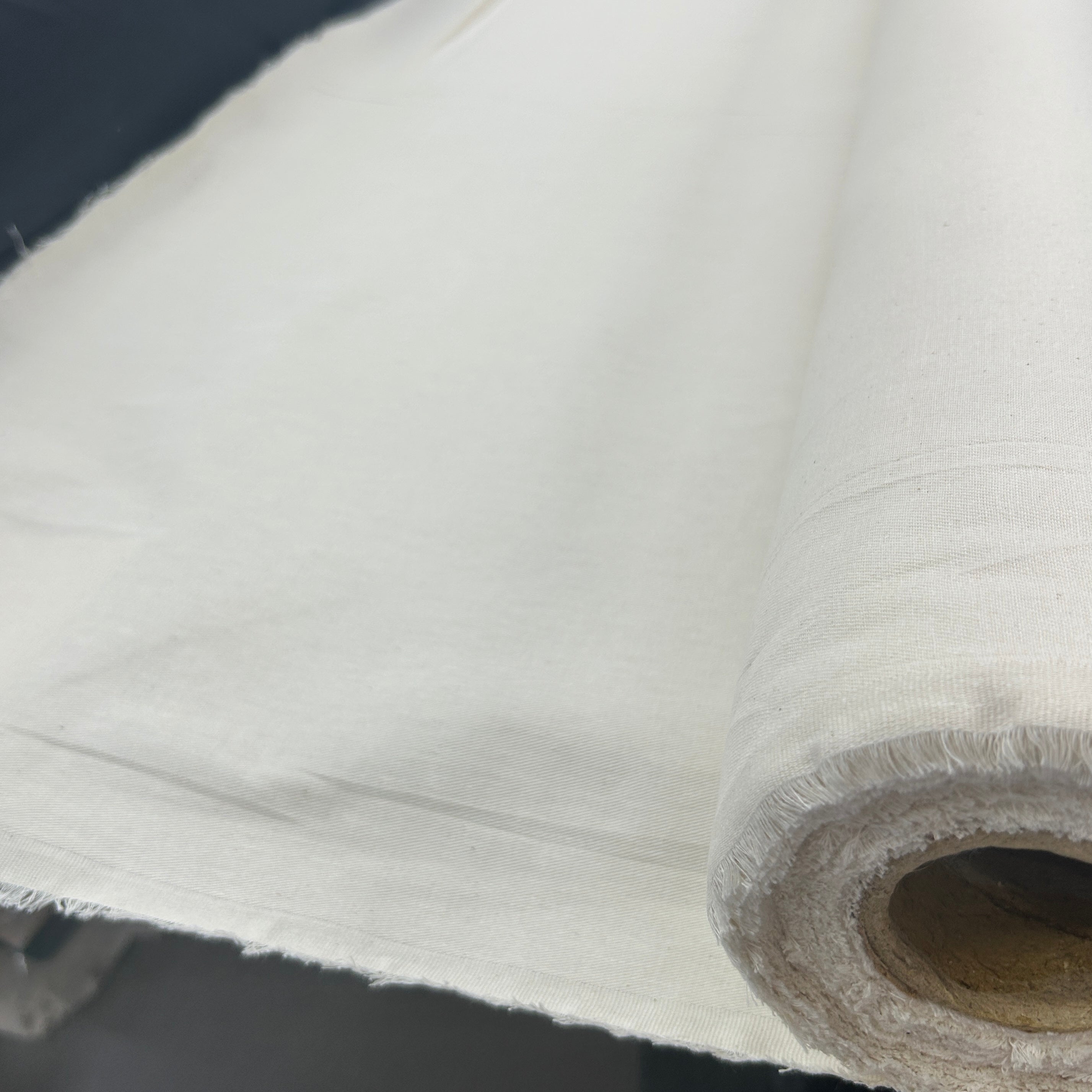 Roll of natural white heavyweight plain calico canvas fabric with a rustic texture.