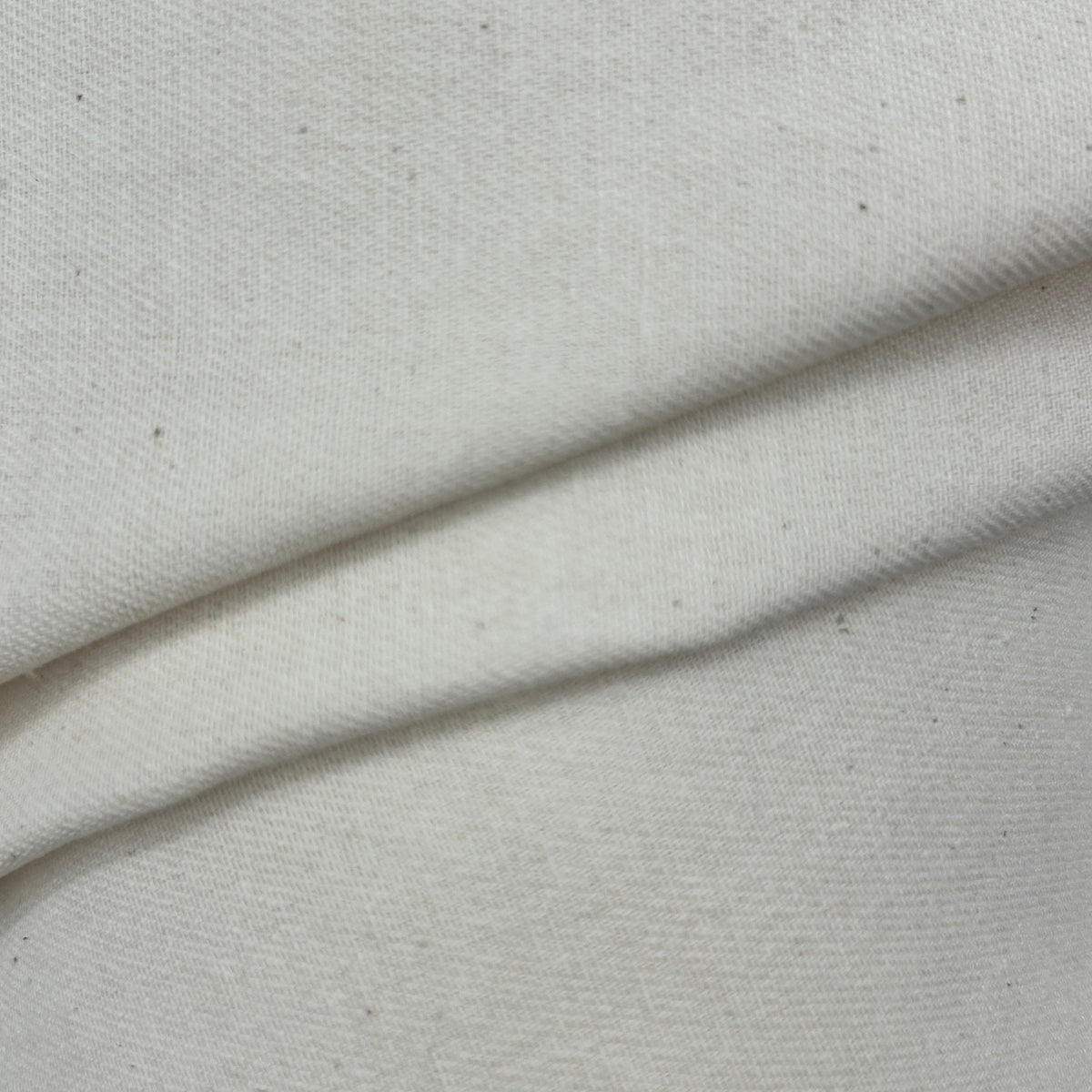 Close-up of folded natural white plain calico canvas heavy fabric with a rustic weave texture.