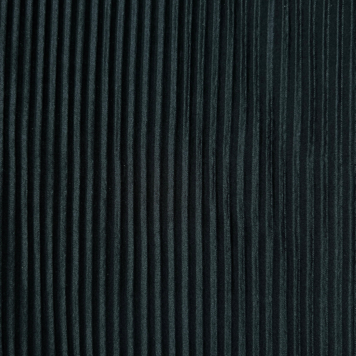A close-up of a dark charcoal gray pleated fabric texture with vertical pleats.