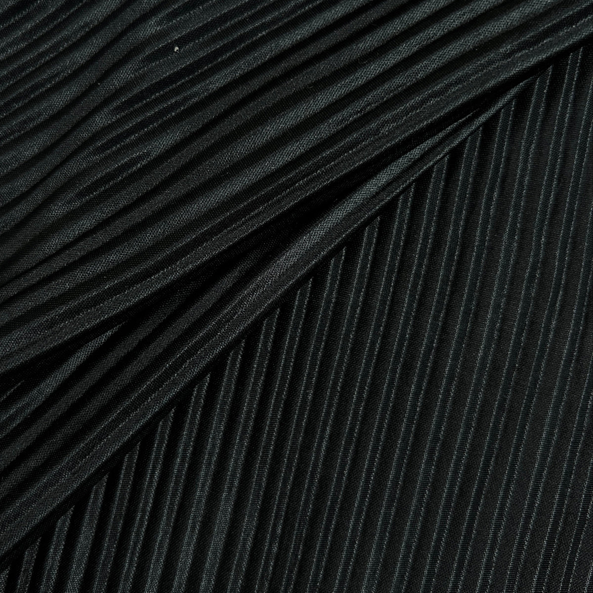 Close-up of a black pleated fabric with tightly folded vertical pleats and a soft sheen.