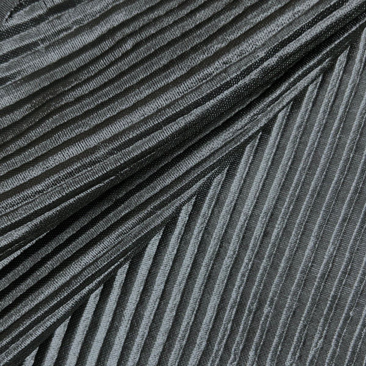A close-up of a dark gray pleated fabric with a textured, metallic-like sheen, arranged diagonally.