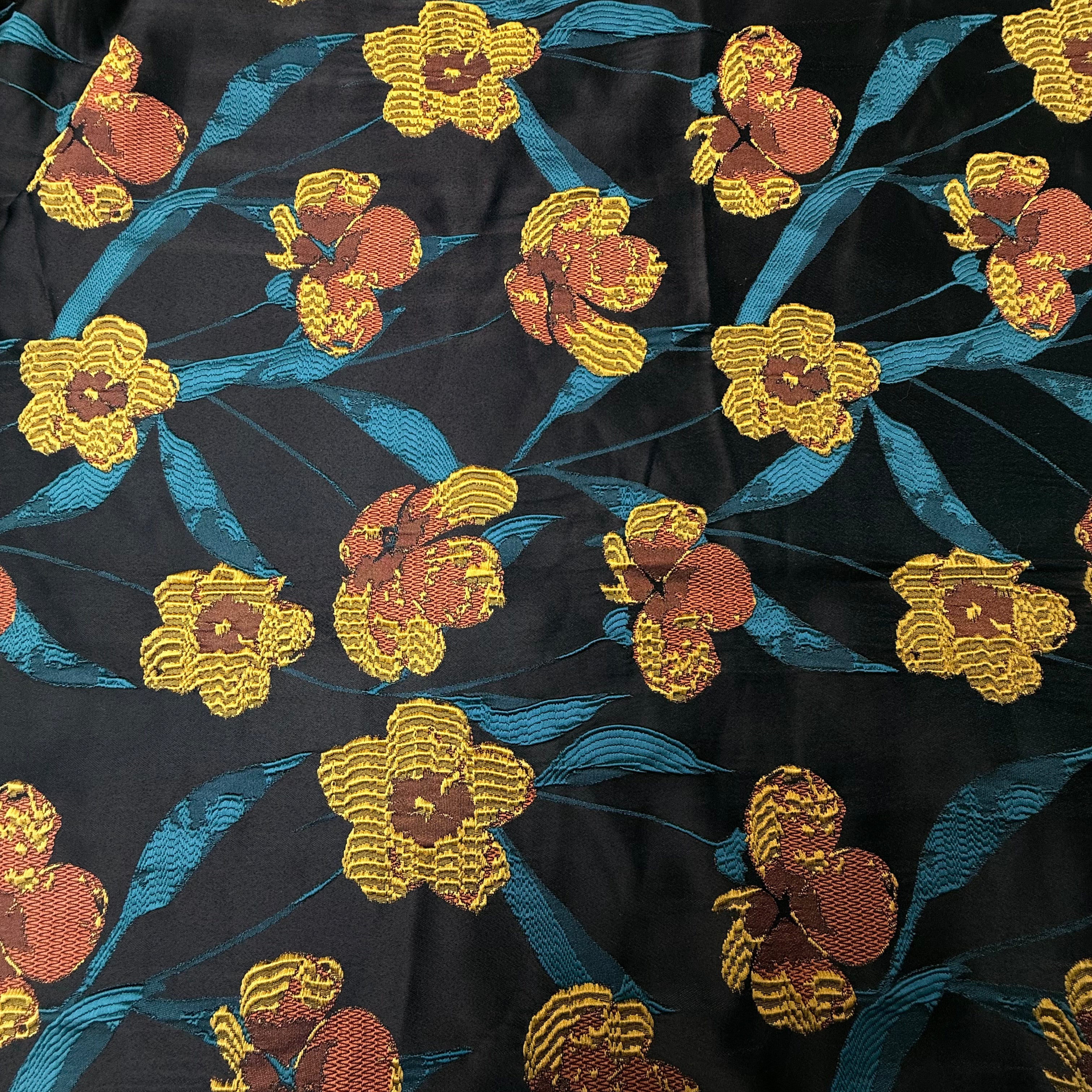 Black floral jacquard fabric with woven yellow and orange flowers and blue leaves.