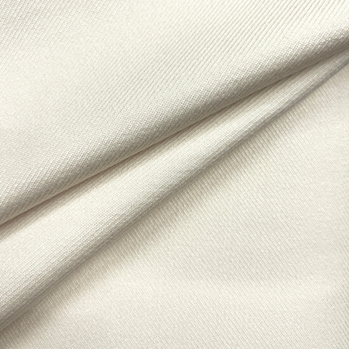 A close-up of draped off-white fabric with a fine ribbed texture, showing soft folds and shadows.