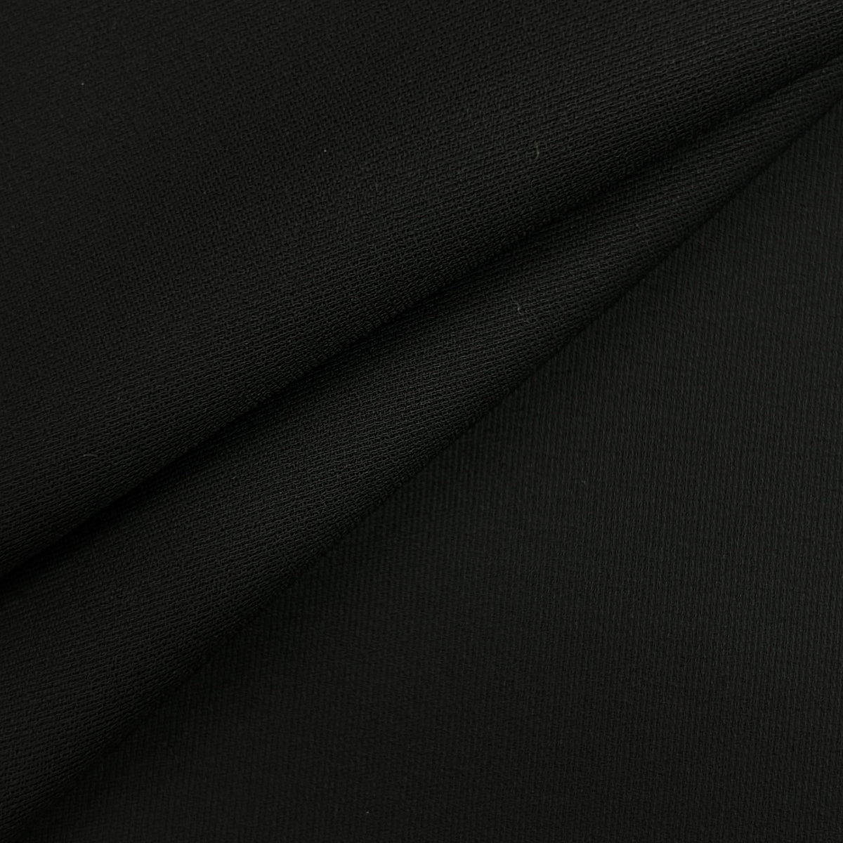 A close-up of black fabric with a fine ribbed texture and soft diagonal folds.