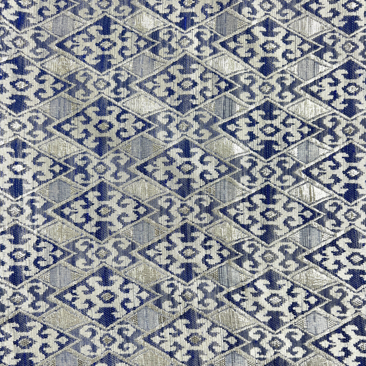 A close-up of a woven fabric with a repeating geometric diamond pattern in navy blue and light beige.
