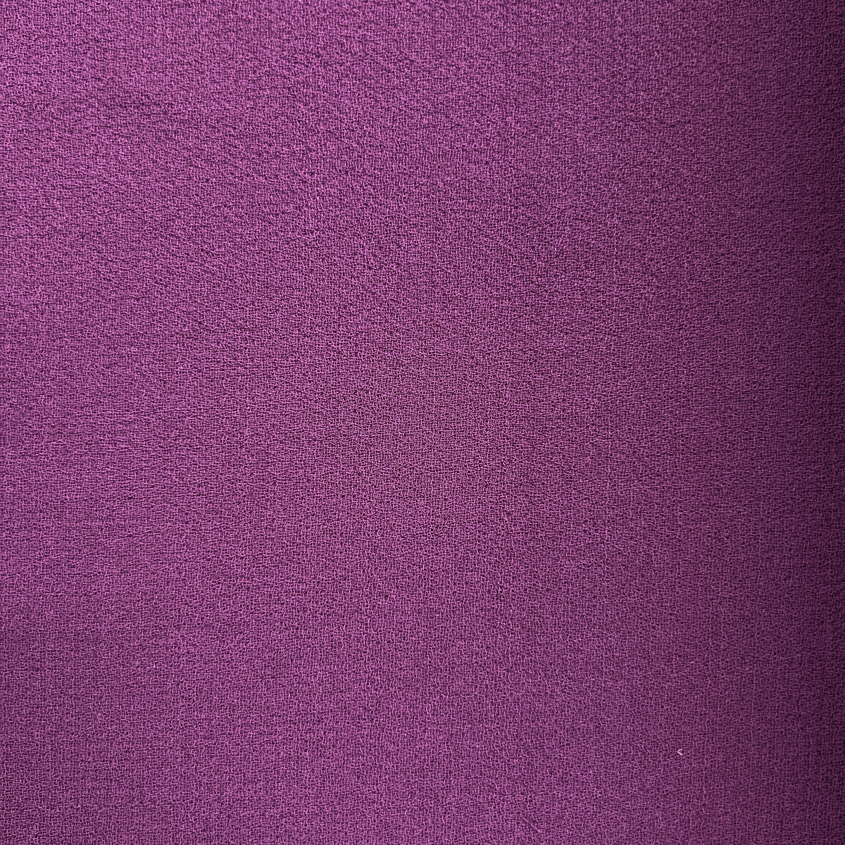 A close-up of a textured purple fabric, showing a fine woven pattern with subtle shading.