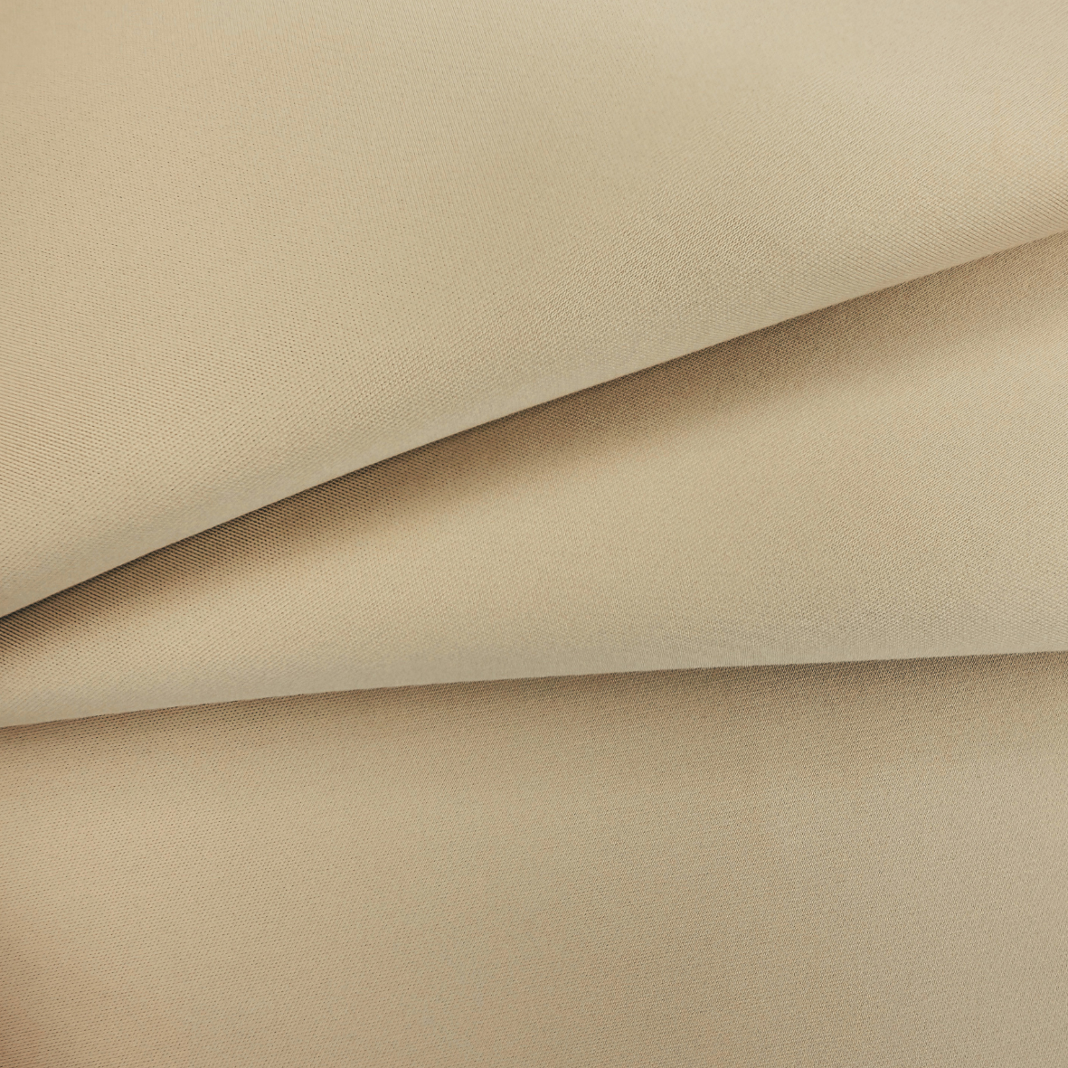 A close-up of draped beige fabric with a fine woven texture, showing soft folds and shadows.