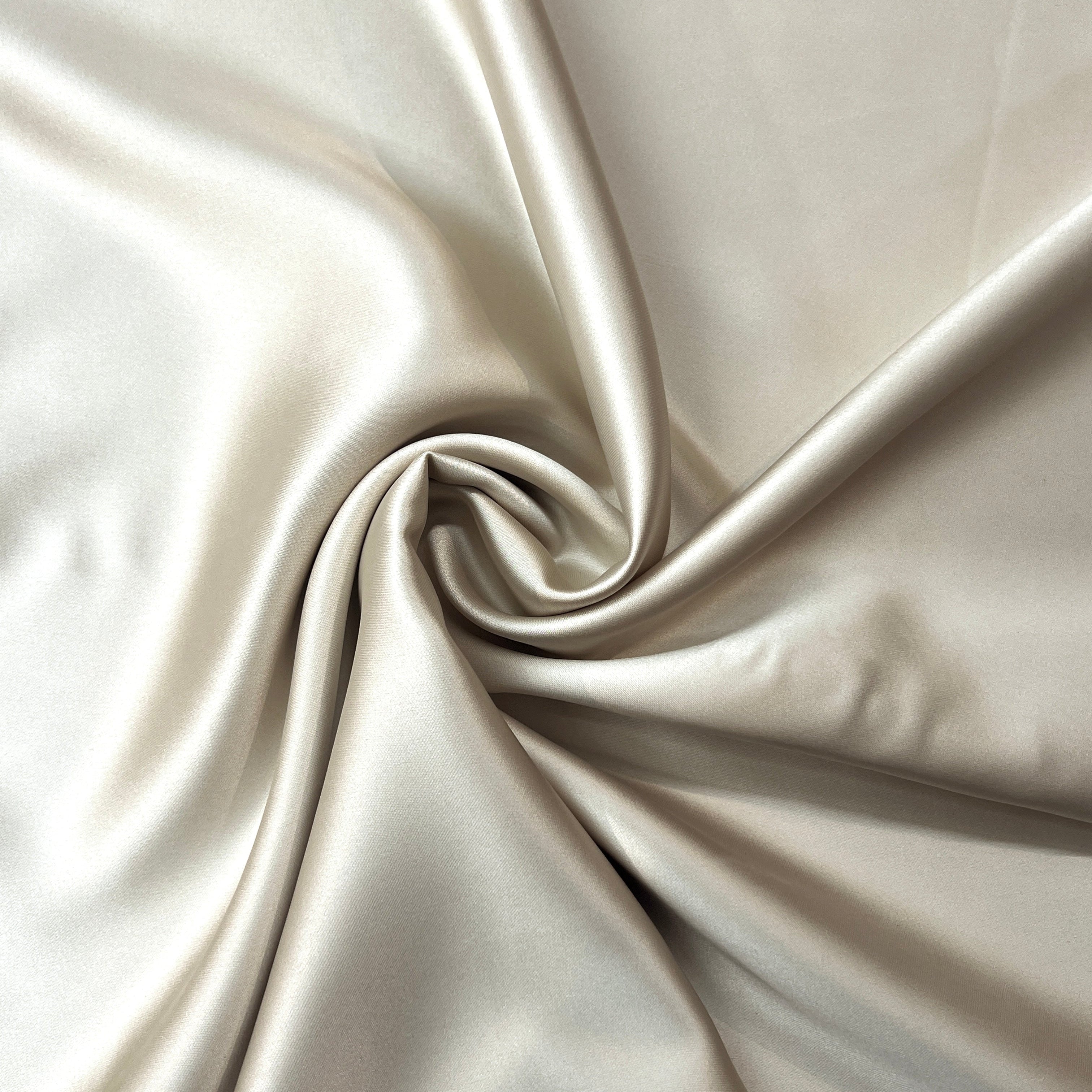 Close-up of beige satin fabric with folds
