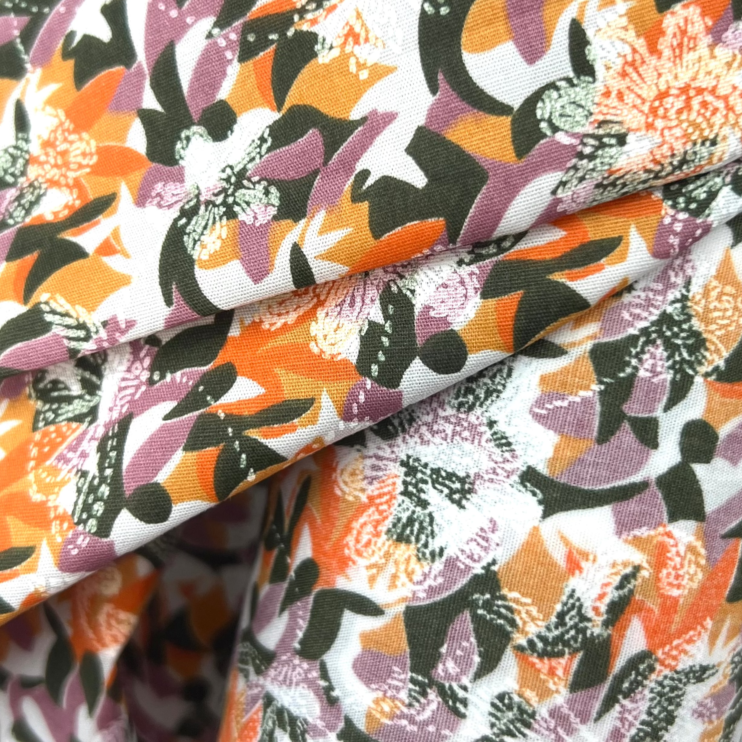 Close-up of colorful floral fabric with orange, purple, and black patterns.