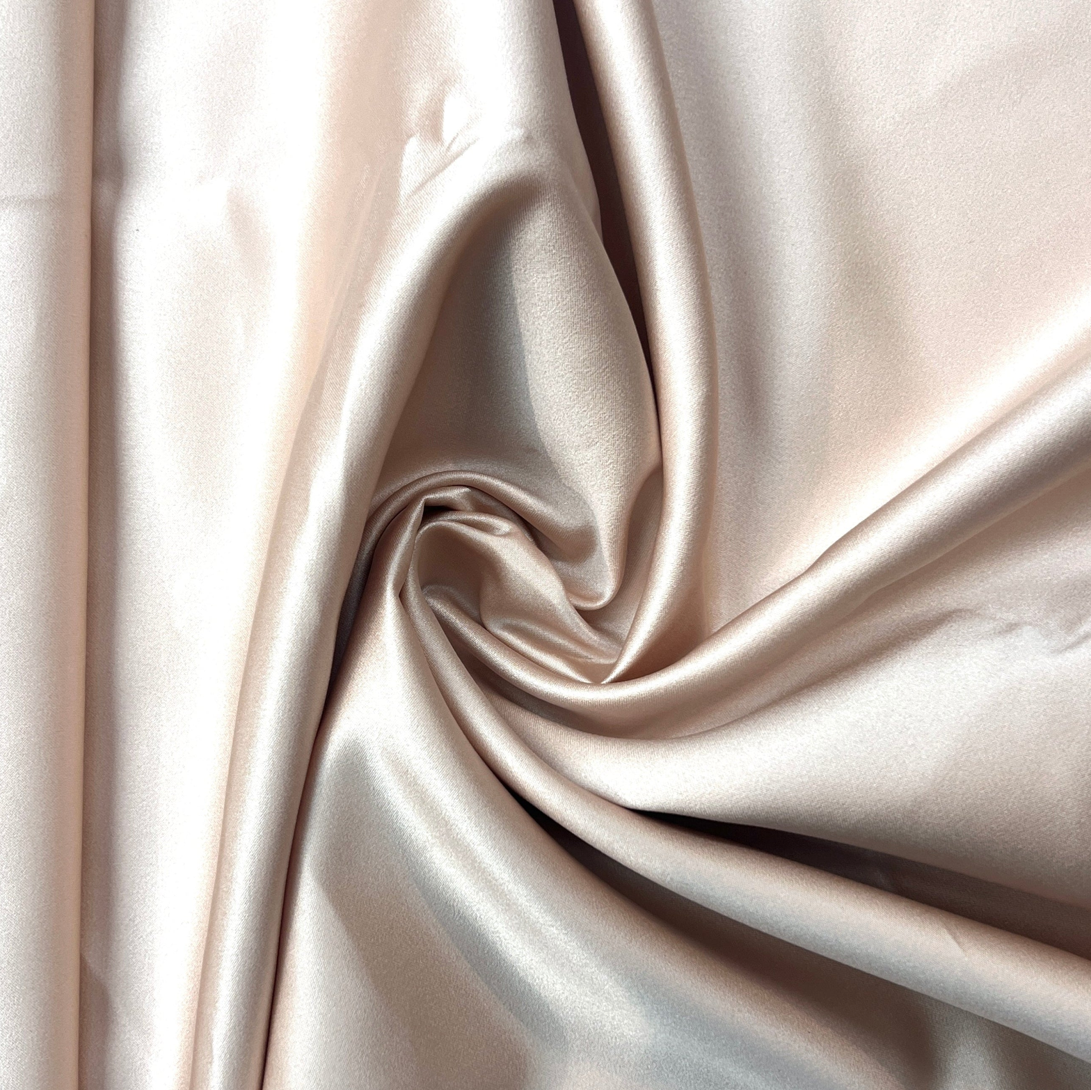 Close-up of beige satin fabric with folds