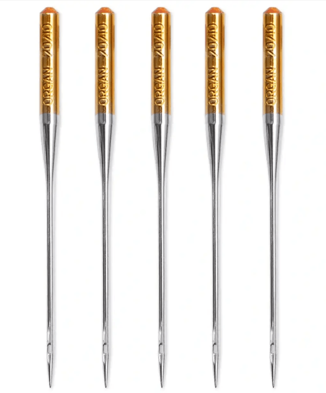 Five silver-colored sewing machine needles with gold tops.