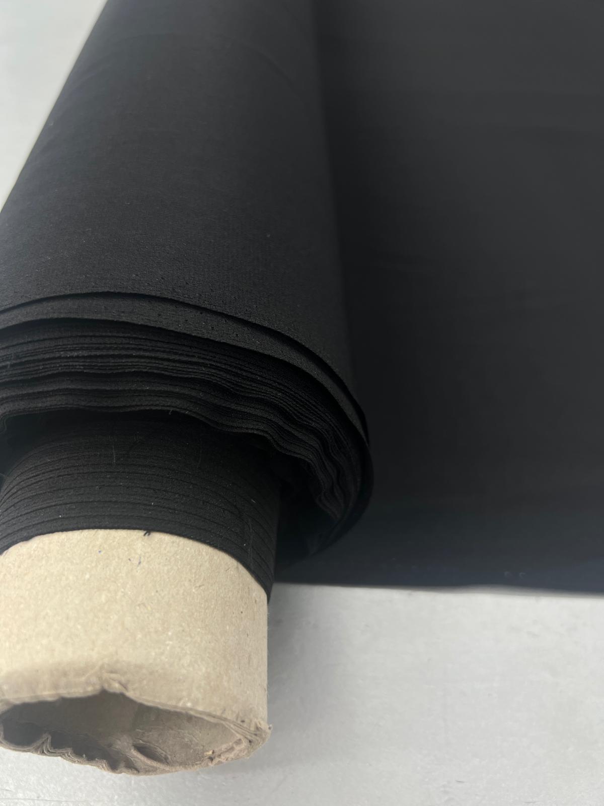Roll of black silk crepe de chine fabric with a matte finish and pebbled texture.